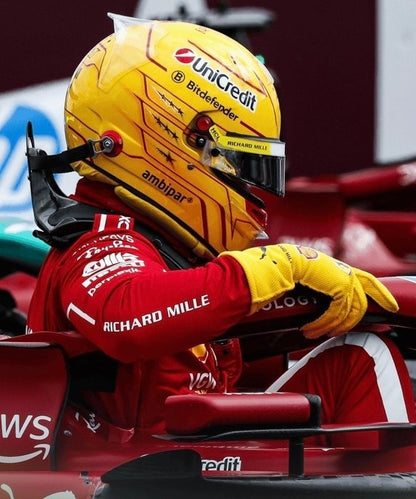 Lewis Hamilton in a red 2025 Ferrari F1 racing suit and yellow helmet sitting in a Formula 1 car - Kartx Gear