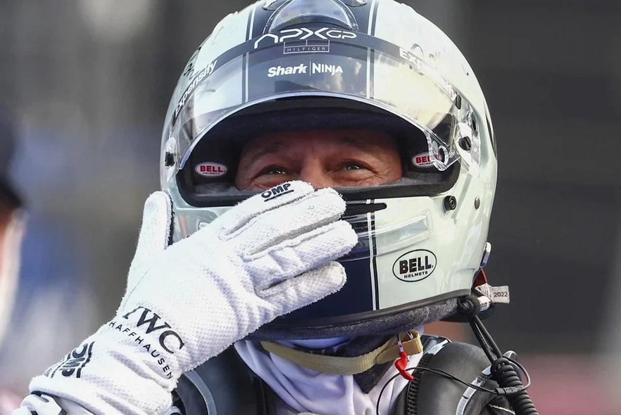Brad Pitt wearing a 2025 F1 The Movie racing helmet with visible branding, holding their hand up to the visor - Kartx Gear